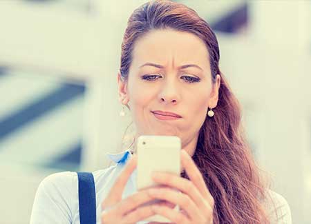 A woman looks at her mobile phone confused about whether she should use small claims court or a debt collection agency