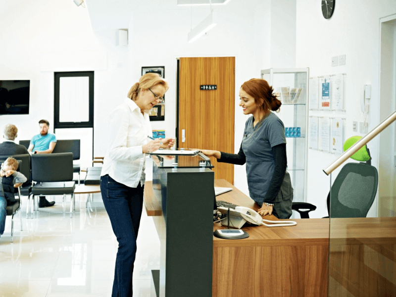 A receptionist checks in a patient at the dentist