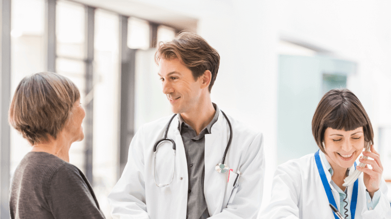 A doctor interacts with a patient, while another doctor speaks on the phone