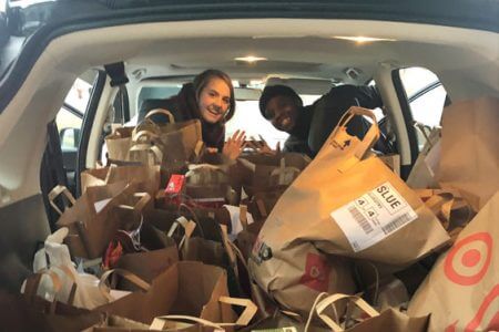 Two IC Systems employees posing with a car full of food donations