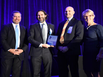 IC System employees posing on a stage holding an award